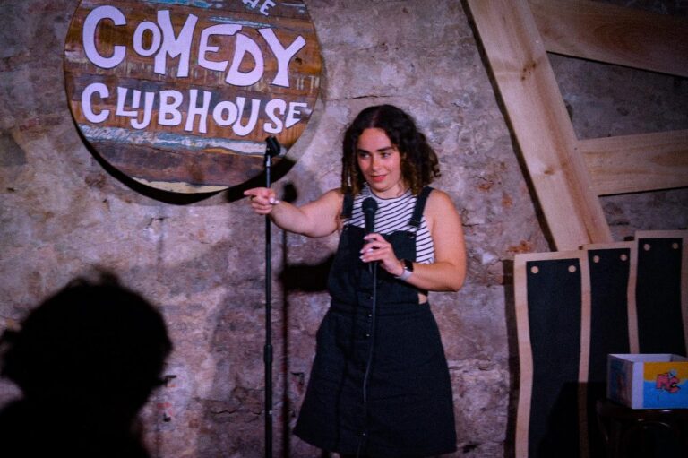 Mariah Girouard points while performing stand-up comedy at the comedy clubhouse in Barcelona